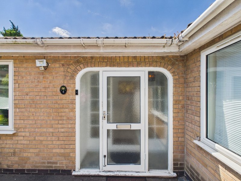 Brick bungalow exterior with white-framed door, windows and guttering