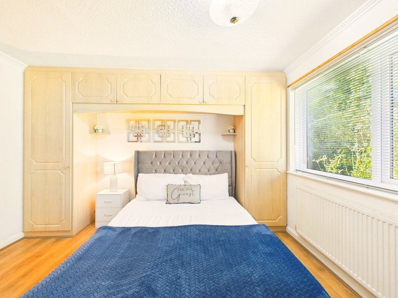 Bright bedroom with double bed, built-in wardrobe, wooden floor and large windows
