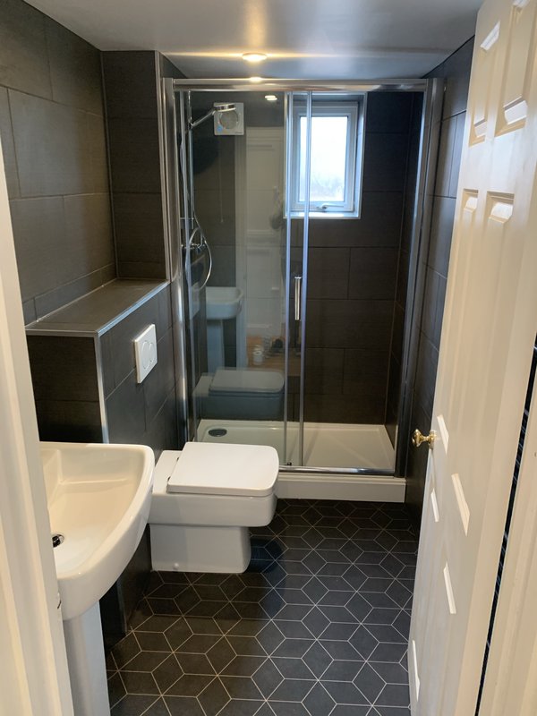 Modern bathroom with shower enclosure, toilet, sink and geometric floor tiles