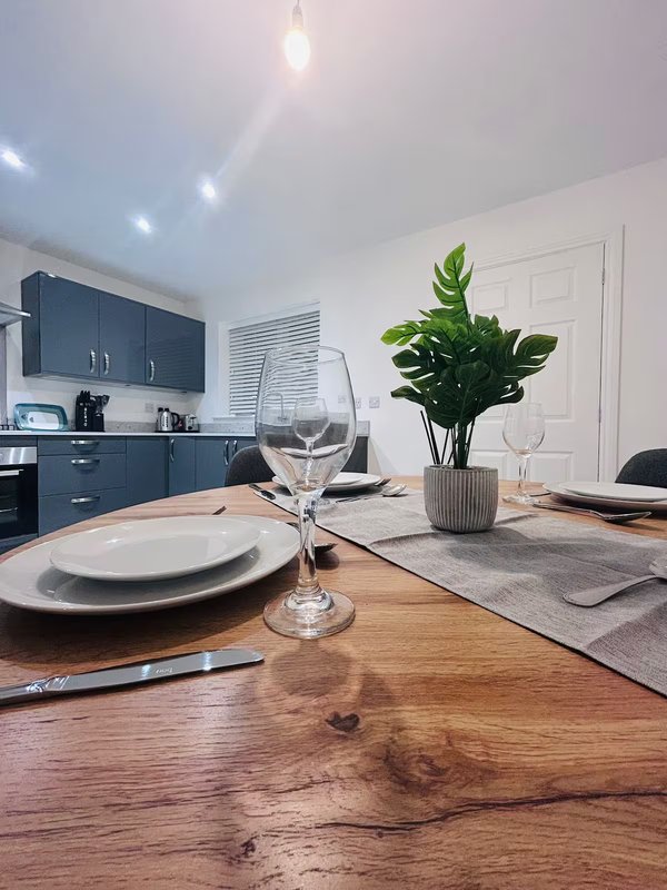 Modern kitchen-dining area with wooden table, place settings, and potted plant