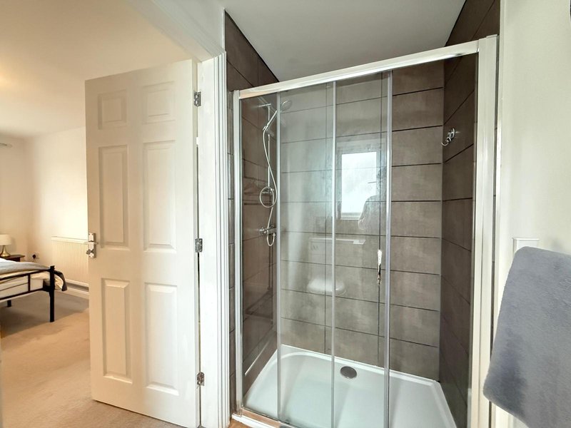 Modern bathroom with glass-enclosed shower cubicle, white frame and grey tile surround