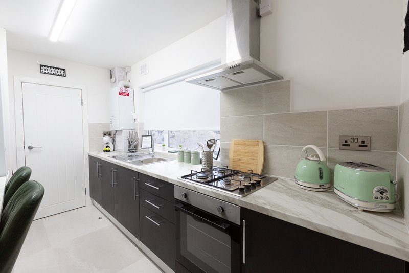 Modern kitchen with black cabinetry, stainless steel appliances, white countertops and tiled backsplash