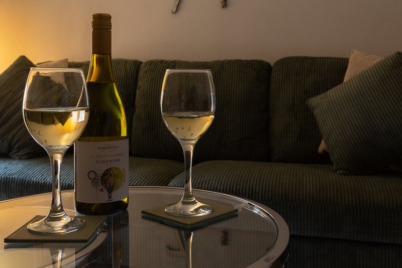 Living room with grey sofa, wine bottle and glasses on table, warm lighting