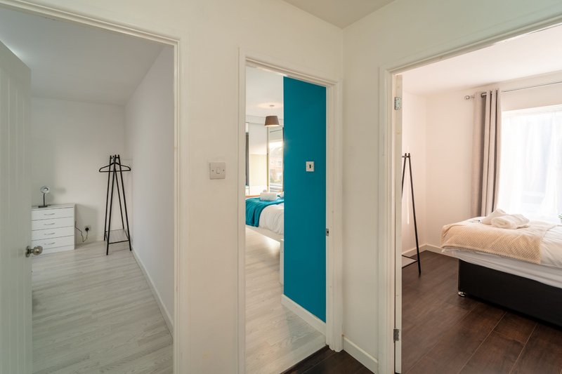 Hallway connecting bedroom and dressing room with teal accent door and white walls