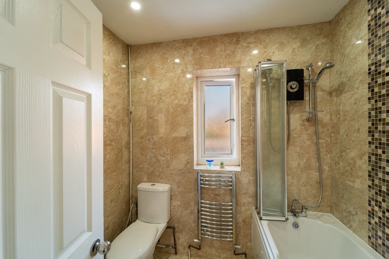 Modern bathroom with toilet, vanity unit, bathtub and glass shower enclosure