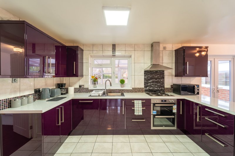 Modern kitchen with purple cabinets, white countertops, stainless steel appliances and breakfast bar