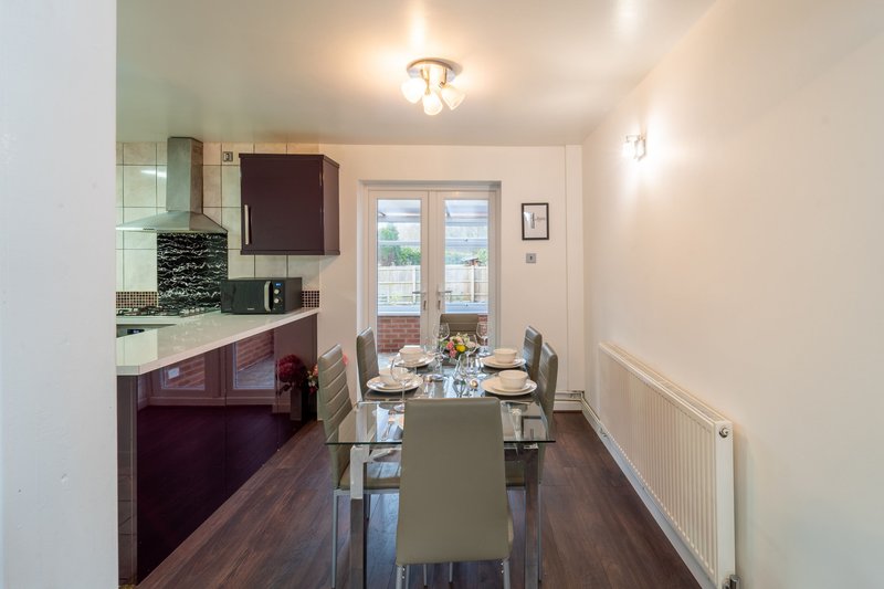 Modern kitchen and dining area with dark cabinetry, island table and glass doors