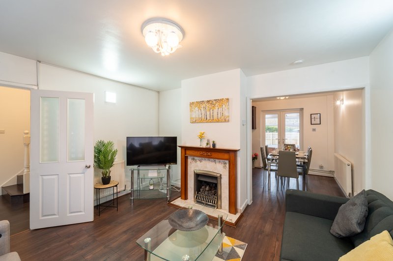 Bright living room with fireplace, TV, sofa, and open-plan dining area visible