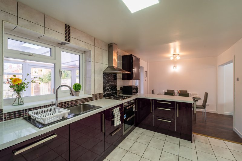 Modern kitchen with dark cabinets, stainless steel appliances, and large window overlooking garden