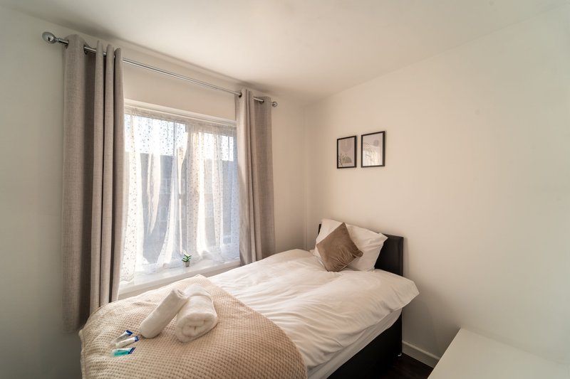Bright bedroom with double bed, large window with grey curtains, and wall art