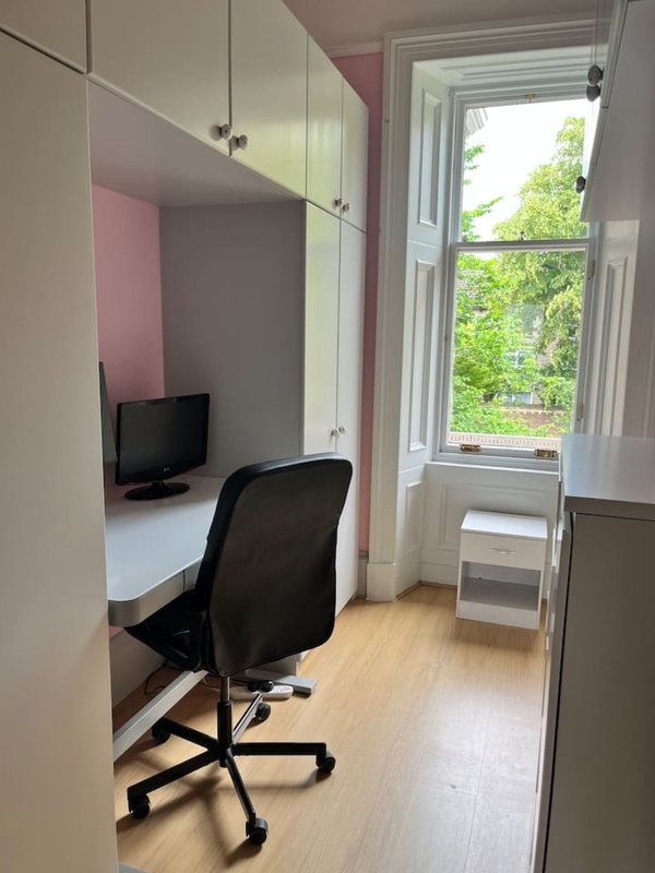 Compact home office with desk, black chair, monitor and window overlooking garden