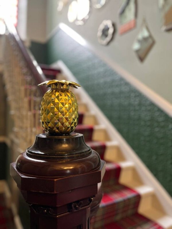 Decorative golden pineapple ornament on staircase newel post, hallway view