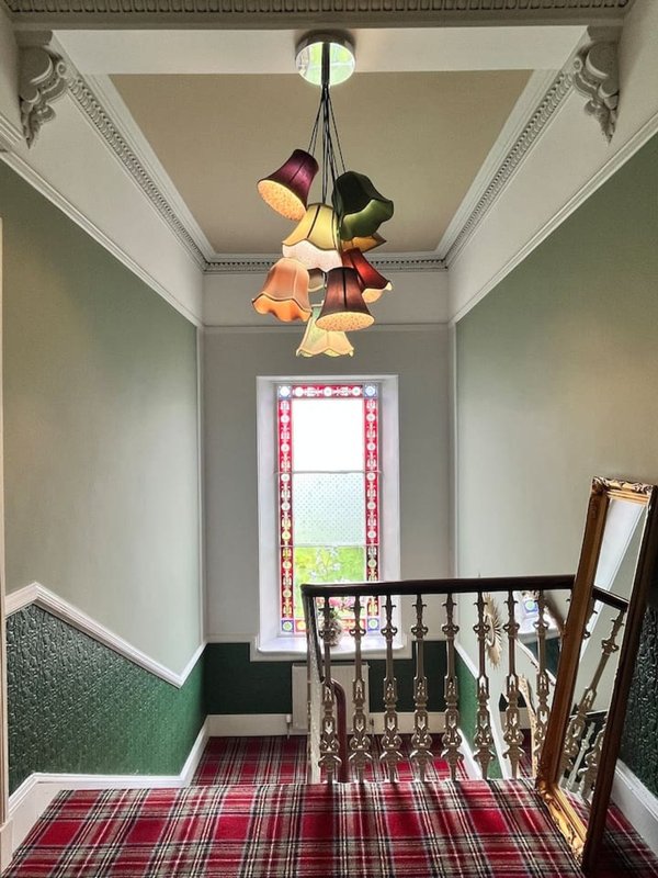 Stairwell landing with colorful pendant light, tartan runner, and decorative railings
