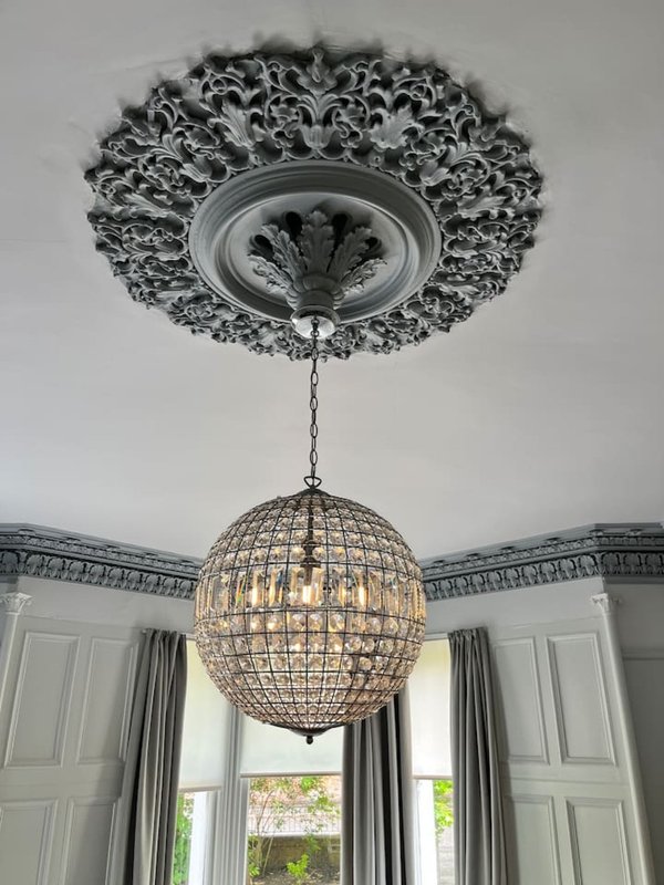 Ornate ceiling rose with crystal globe pendant light and tall windows