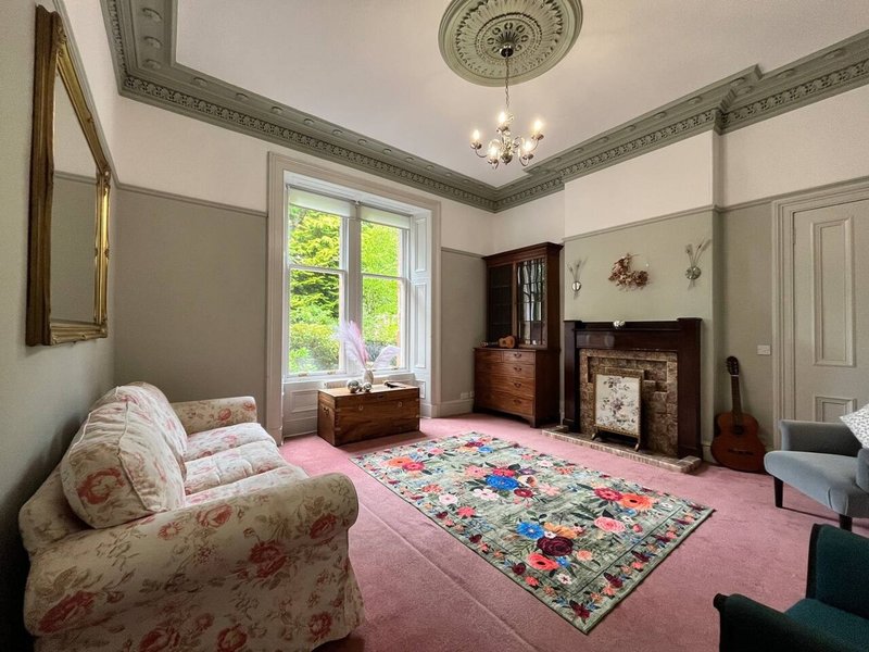 Traditional bedroom with floral armchair, pink carpet, fireplace and period ceiling details