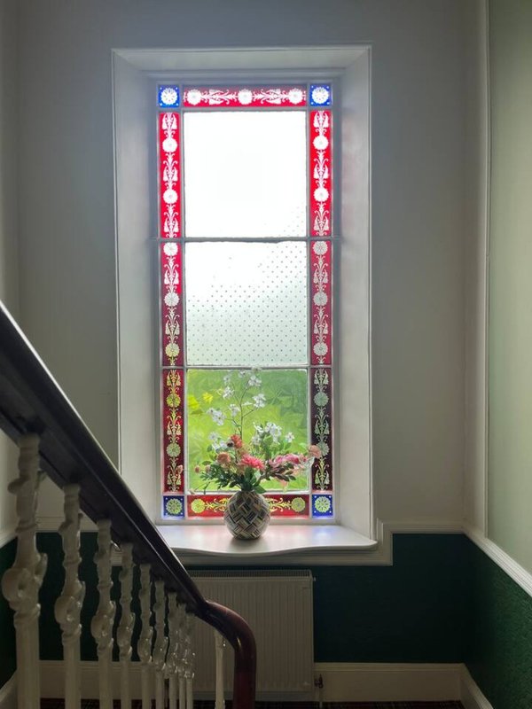 Stairwell with decorative stained-glass window overlooking garden with potted plant