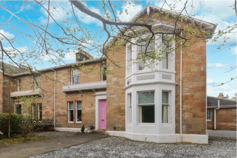 Brick Victorian house with white bay window, pink door, and gravel driveway