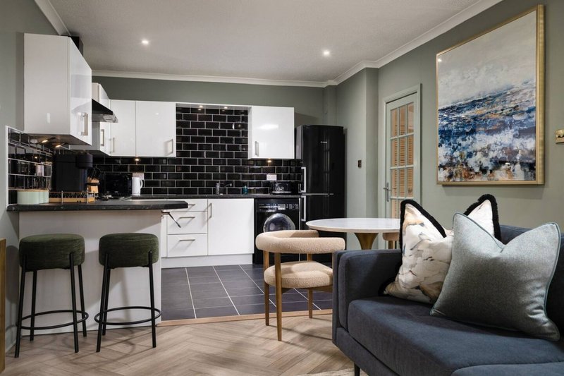 Open-plan kitchen and living room with white cabinetry, black subway tile backsplash, and seating area