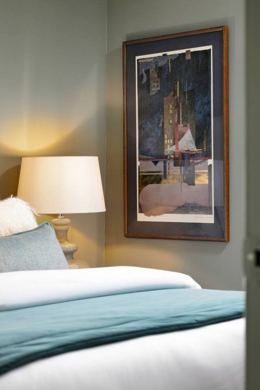 Bedroom with double bed, bedside lamp, and framed artwork on wall