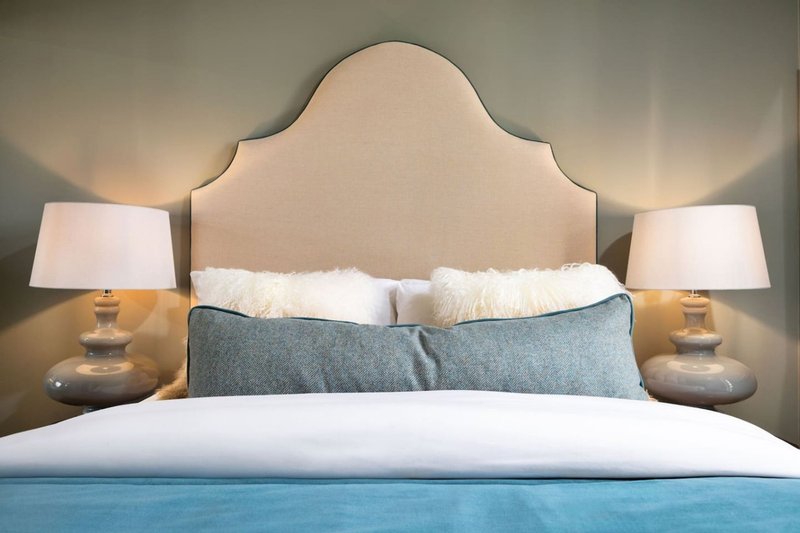 Bedroom with upholstered headboard, white bedding, decorative pillows, and bedside lamps
