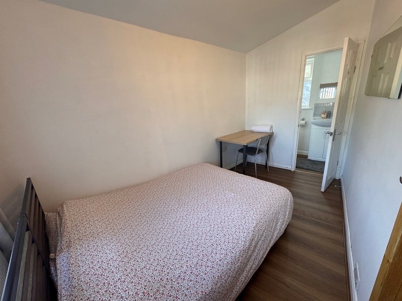 Small bedroom with double bed, wooden floor, desk and chair, white walls