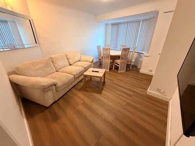Living room with cream sofa, wooden floor, dining table and vertical blinds