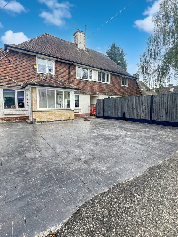 Brick semi-detached house with driveway, paved patio area and dark wooden fence