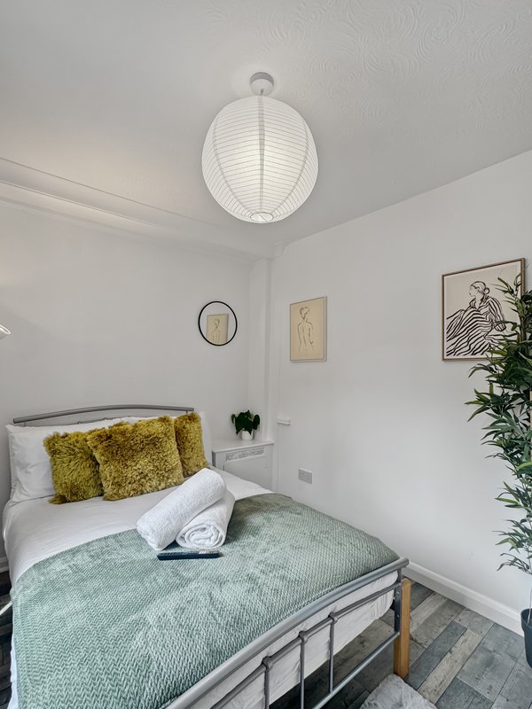 Bright bedroom with single bed, yellow cushions, pendant light, and wall art