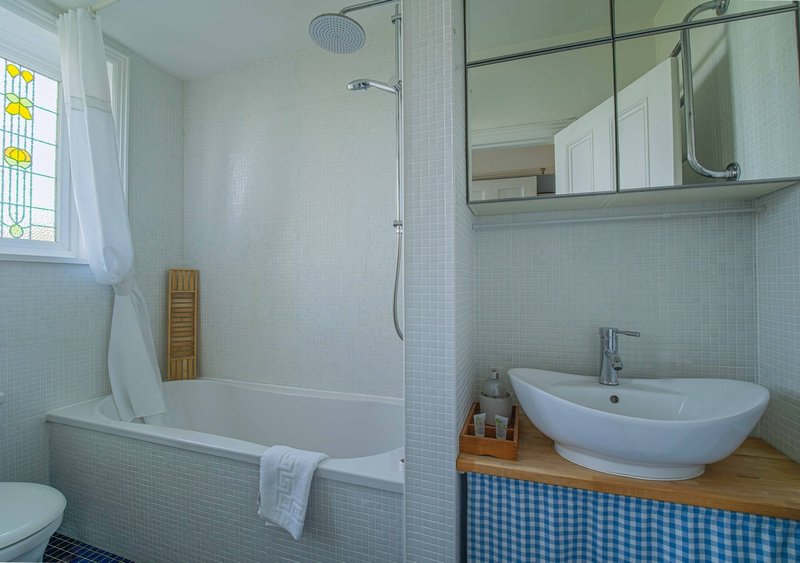 Modern bathroom with white subway tiles, bathtub, curved sink, mirror and window