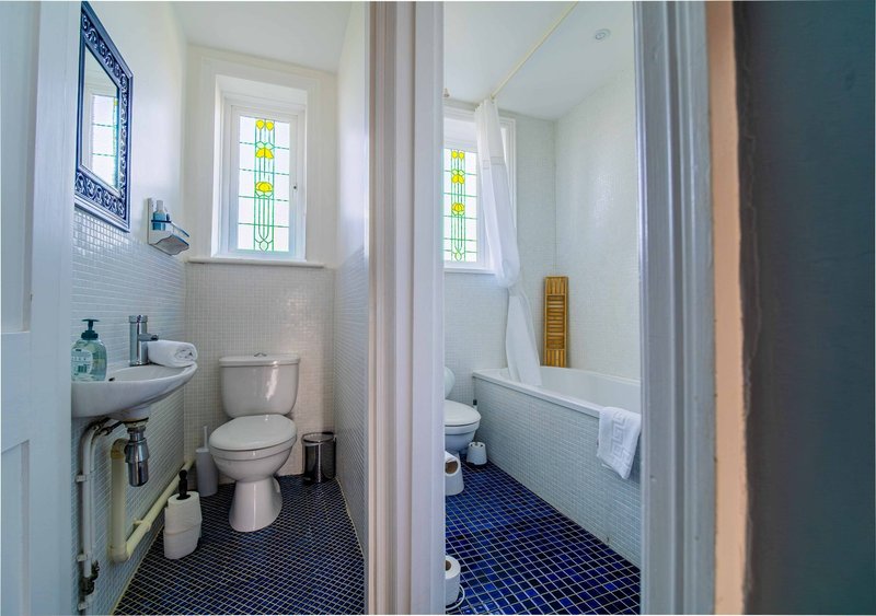 Bathroom with toilet, sink, and window with stained glass panes