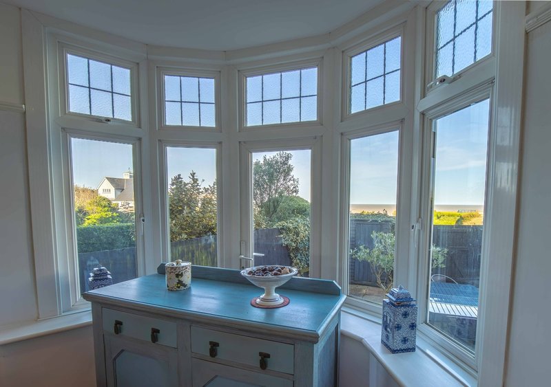 Bay window with blue dresser, decorative items, and views of garden and countryside beyond