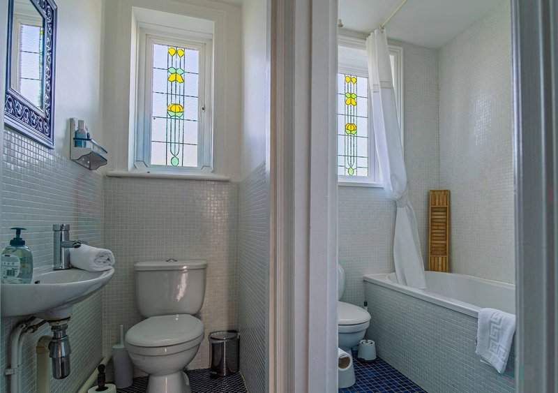 Bathroom with toilet, sink, bath tub and stained glass windows