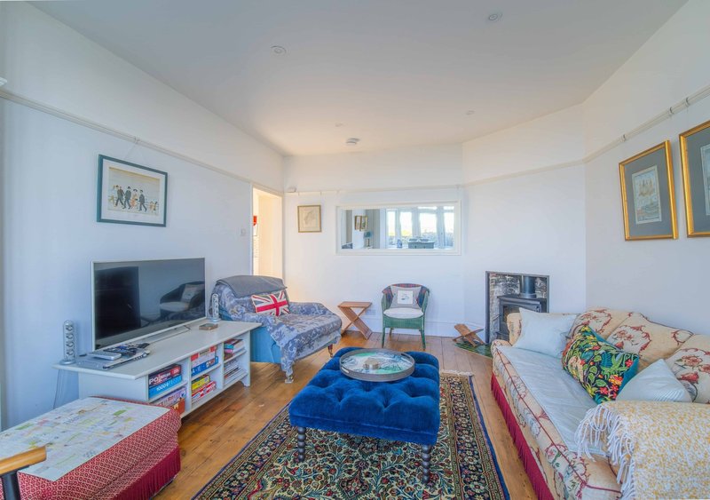 Bright bedroom with two single beds, TV, blue bean bag chair and wooden flooring