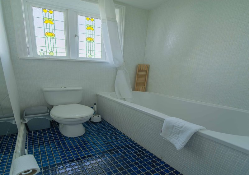 Bathroom with toilet, bathtub, blue tiled floor and stained glass windows