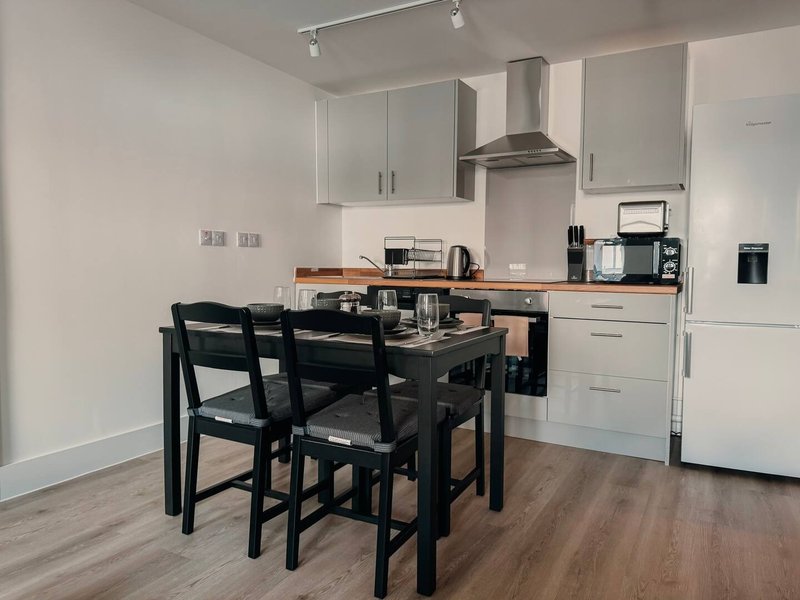 Modern kitchen with white cabinetry, black dining table, chairs, and stainless steel appliances