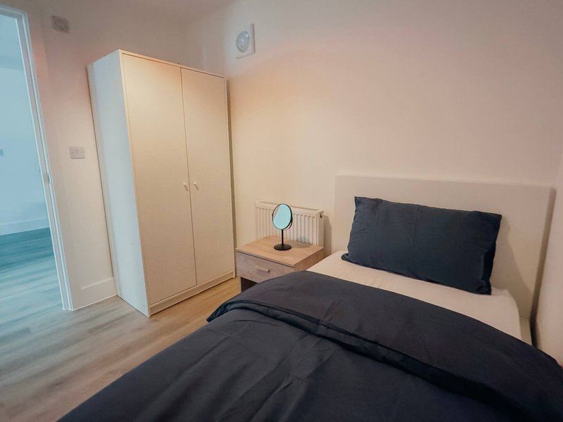 Bedroom with double bed, black bedding, wooden wardrobe, bedside table and mirror