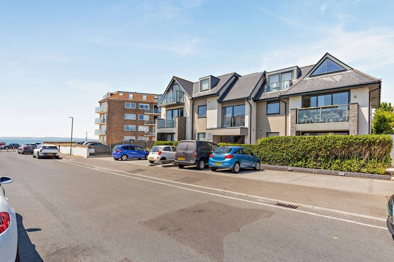 Modern residential building exterior with parking area and street view