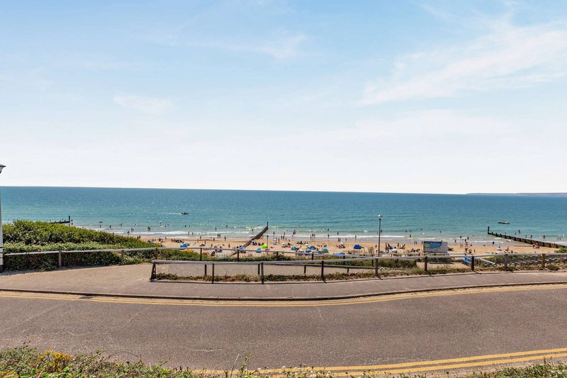 Coastal property view with beach access, seafront promenade and sandy shoreline visible