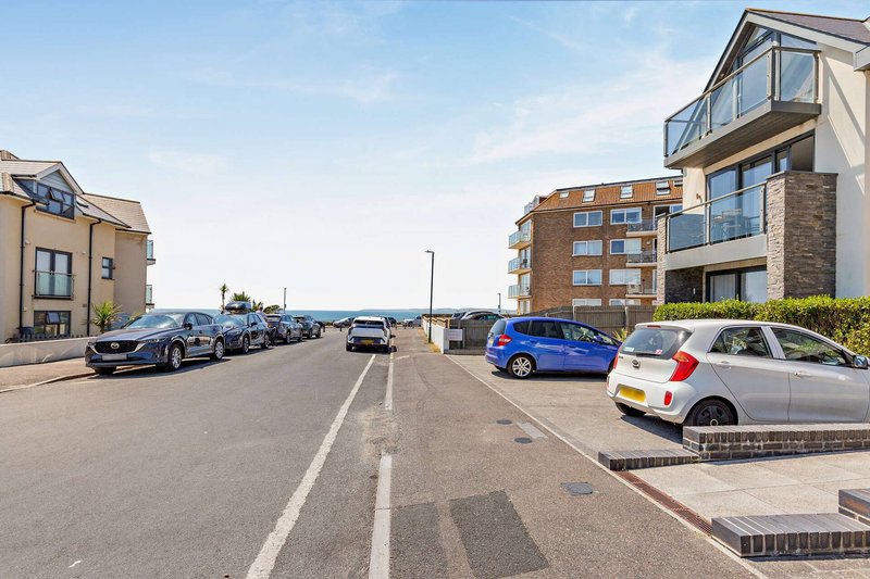 Residential street with parked cars, modern apartment buildings and houses on both sides