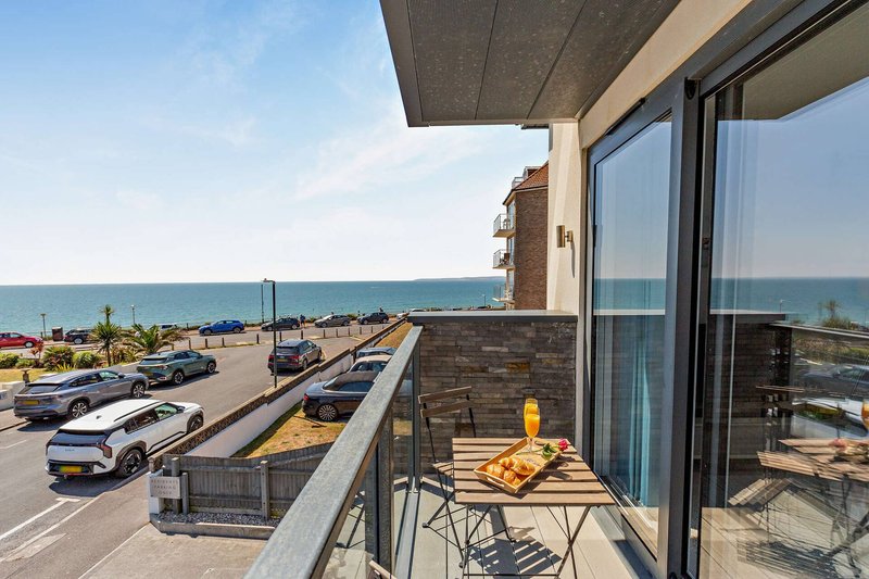 Coastal balcony with sea view, dining table, chairs and seaside promenade below