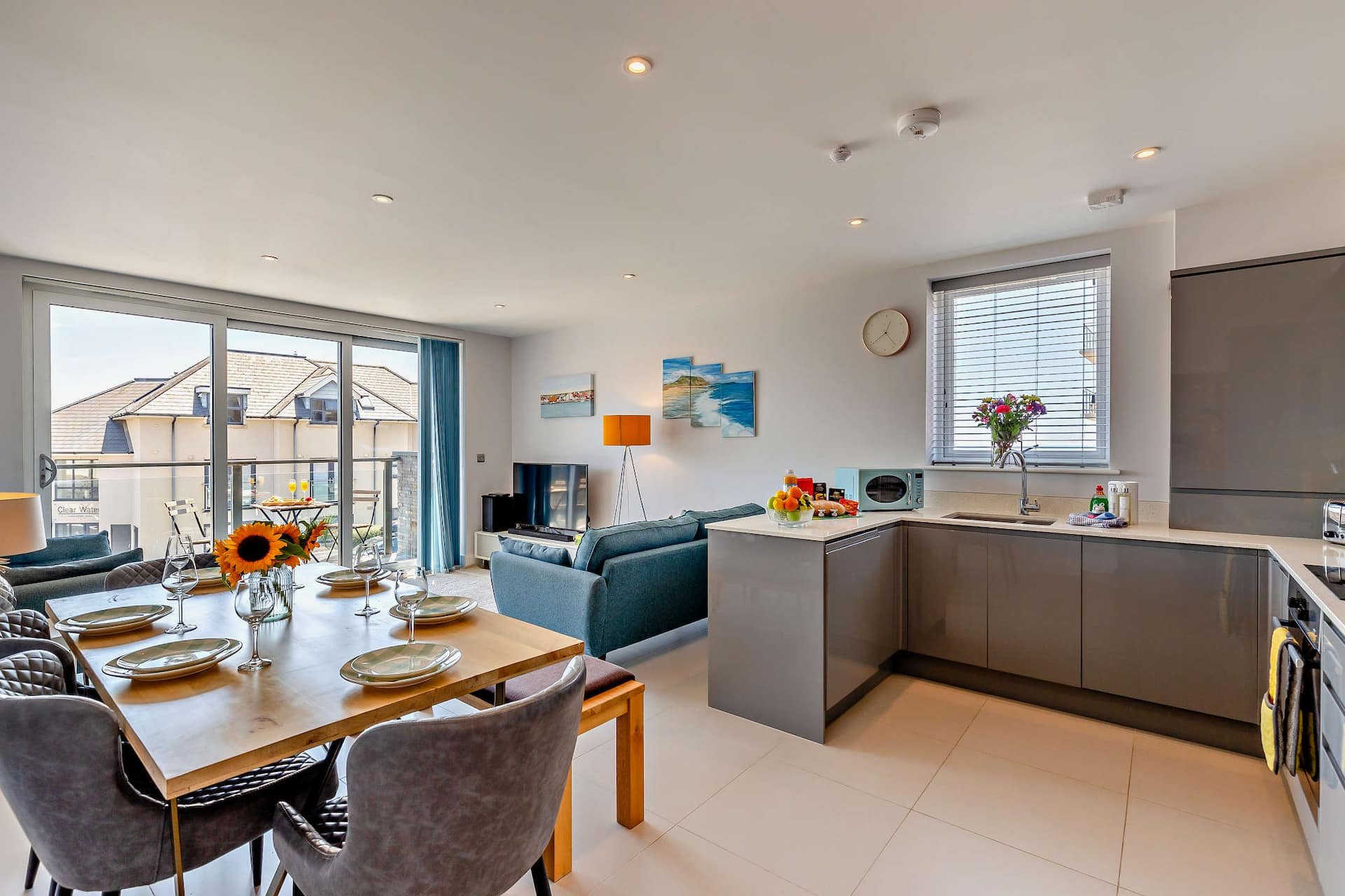 Open-plan kitchen and living area with dining table, sofa, and balcony access