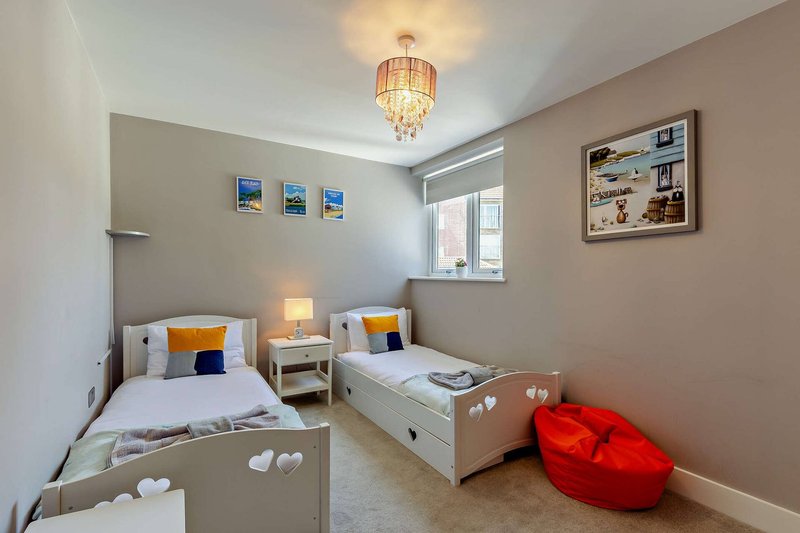 Children's bedroom with two single beds, wooden furniture, cushions, and red bean bag chair