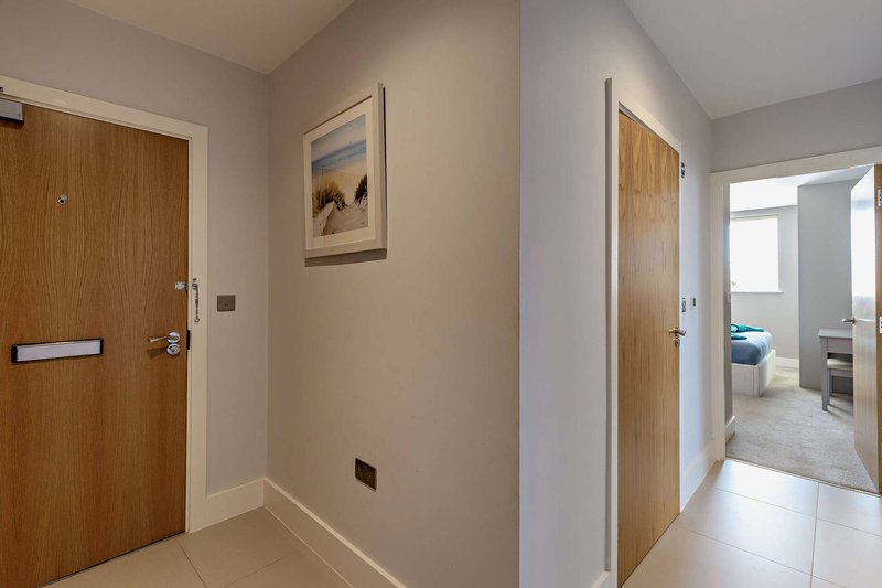 Modern hallway with wooden doors, neutral walls, tiled flooring and framed artwork