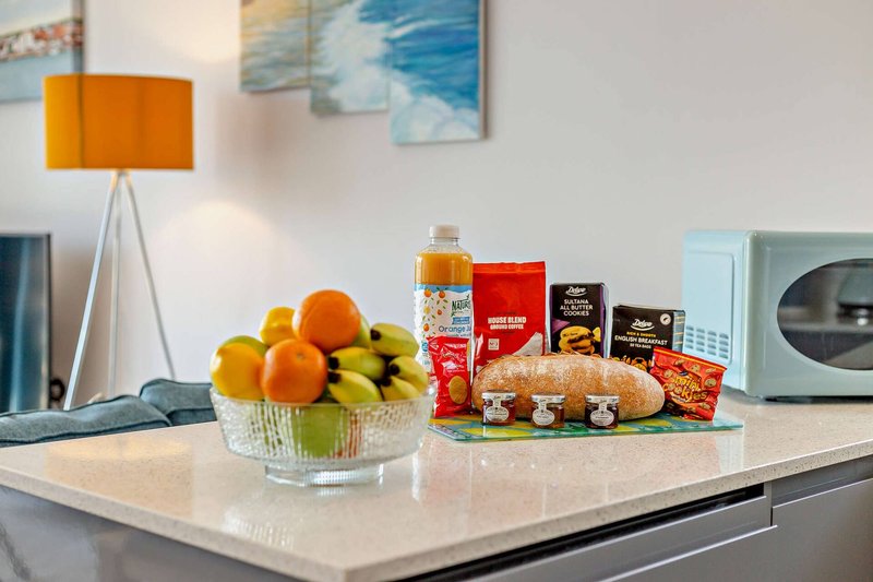 Modern kitchen island with fruit bowl, packaged groceries, and orange table lamp