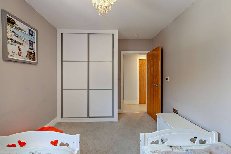 Bright bedroom with two single beds, sliding wardrobe, wooden door and crystal ceiling light