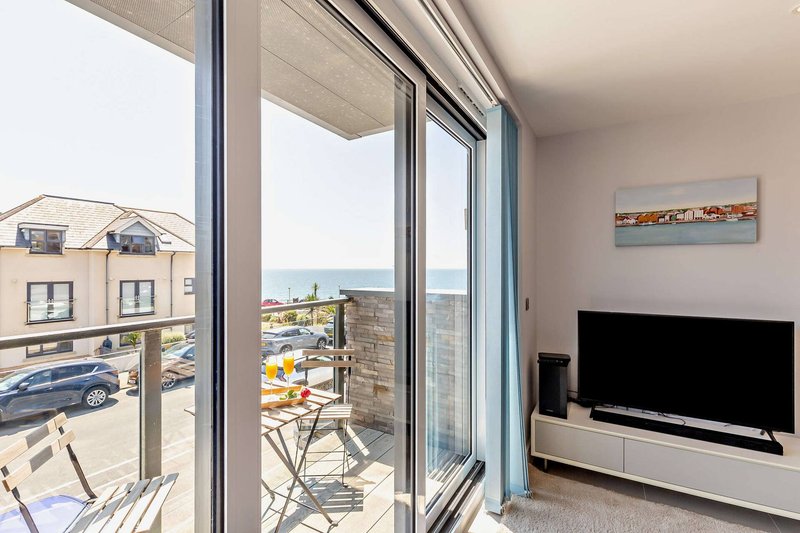 Modern apartment with balcony doors, sea view, and wall-mounted television