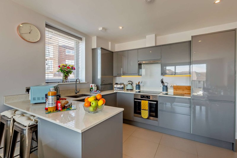 Modern kitchen with gray cabinetry, white island, stainless steel appliances and window view