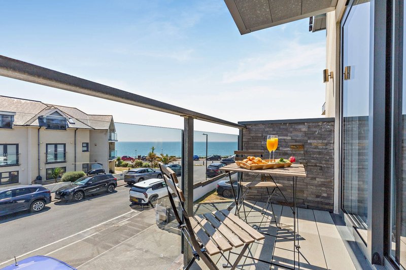 Seaside terrace with seating, table, sea view, and adjacent residential properties