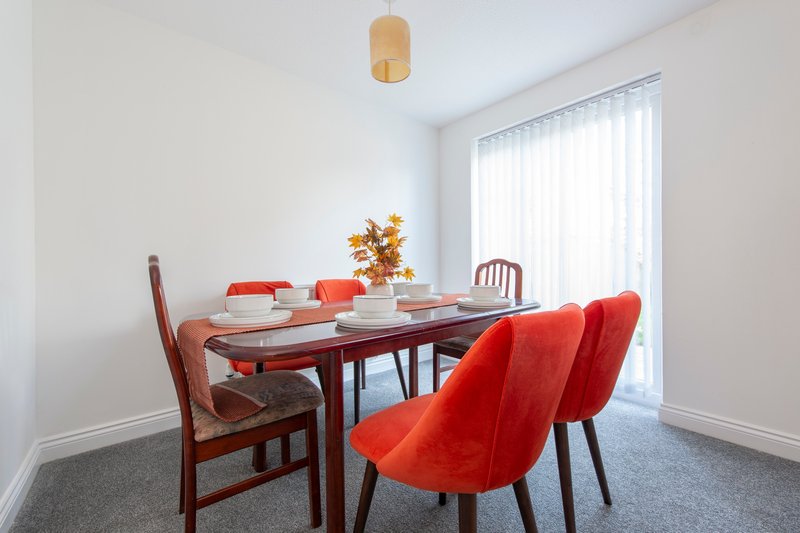 Dining room with red chairs, wooden table, place settings and golden pendant light