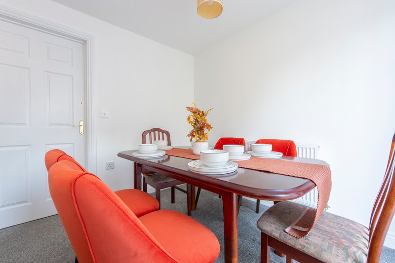 Dining room with wooden table, red upholstered chairs, white door and ceiling light